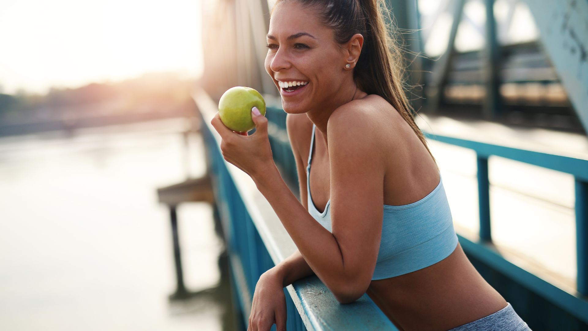 Kobieta, która prowadzi zdrowy styl życia, je jabłko w przerwie podczas biegania.