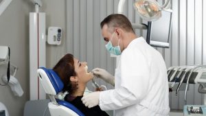 Kiedy warto wybrać się do ortodonty? Na zdjęci u ortodonta bada jamę ustną pacjentki w gabinecie.